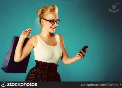 Retro style. Young woman pinup girl in glasses with shopping bag talking on cell phone. Vintage photo.