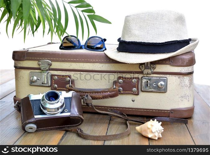 retro suitcase and camera on on wooden table with straw hat and glasses on white background. retro suitcase and camer a on on wooden table withstraw hat and glasses on white background