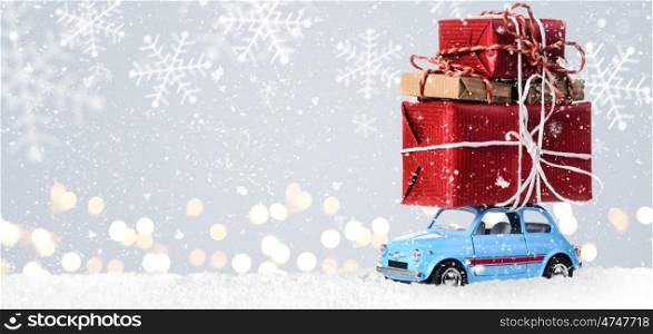 Retro toy car with christmas gifts. Blue retro toy car delivering Christmas or New Year gifts on festive gray background