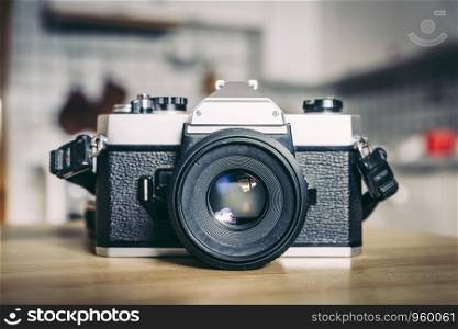Retro vintage photography camera on kitchen table, blurry background
