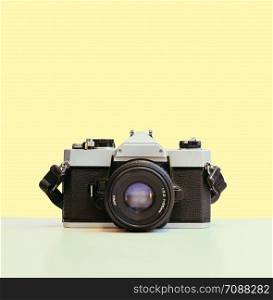 Retro vintage photography camera on yellow colored background