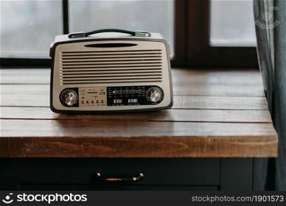 Retro vintage radio on wooden table surface near window. Back to 80s. Music nostalgia and old technology concept. Antique recorder