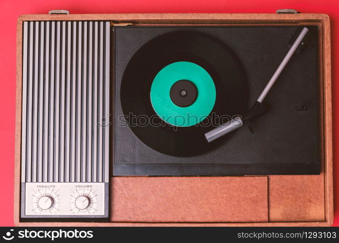 Retro vinyl player and turnable on a red background. Entertainment 70s. Listen to music. Top view.