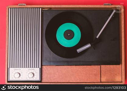 Retro vinyl player and turnable on a red background. Entertainment 70s. Listen to music. Top view.