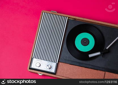 Retro vinyl player and turnable on a red background. Entertainment 70s. Listen to music. Top view.