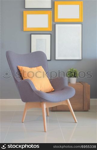 Retry style armchair with orange pillow in living room with wall of picture frame in background