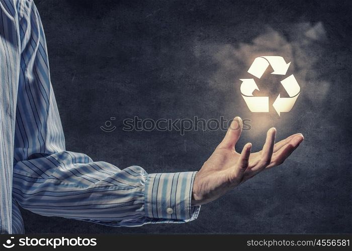 Reuse concept. Businessman holding recycling sign in his hand