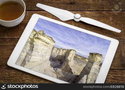 reviewing aeiail image of Monument Rocks in western Kansas prairie on a digital tablet with a cup of tea
