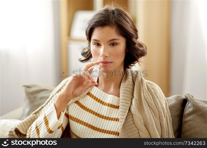rhinitis, medicine and healthcare concept - sick woman using nasal spray at home. sick woman using nasal spray at home
