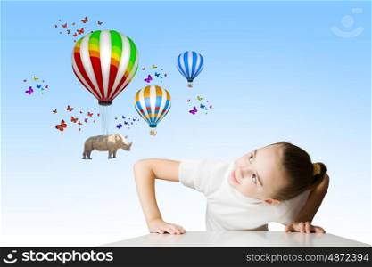 Rhino flying on balloons. Little cute girl looking from under the table