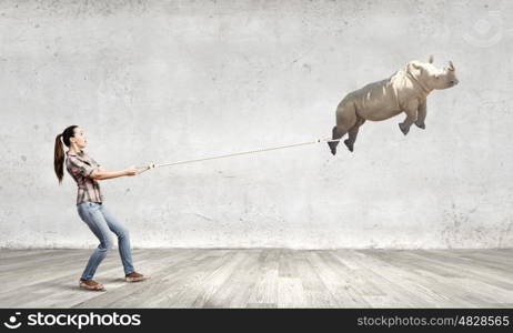 Rhino on lead. Young woman in casual and rhino flying in sky