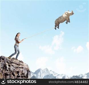 Rhino on lead. Young woman in casual and rhino flying in sky