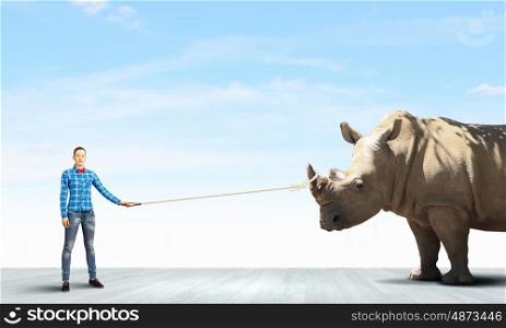 Rhino on lead. Young woman in casual holding rhino on lead