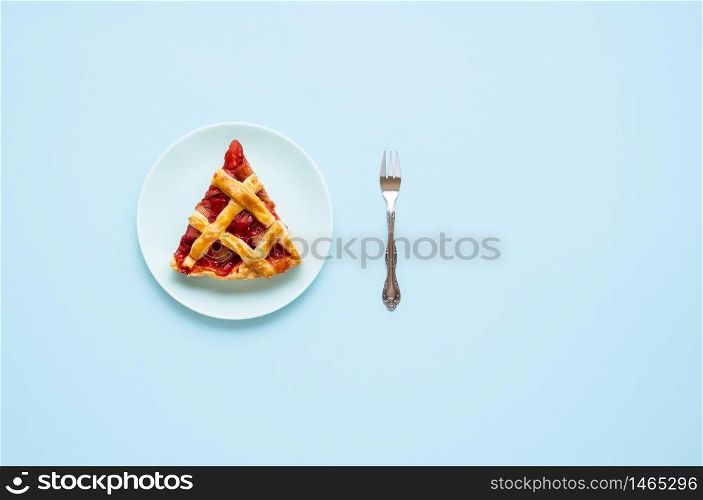 Rhubarb and strawberry pie slice on a plate, isolated on a blue background. Flat lay of one portion of German rhubarb cake. Eating pie concept.