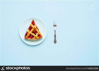 Rhubarb and strawberry pie slice on a plate, isolated on a blue background. Flat lay of one portion of German rhubarb cake. Eating pie concept.