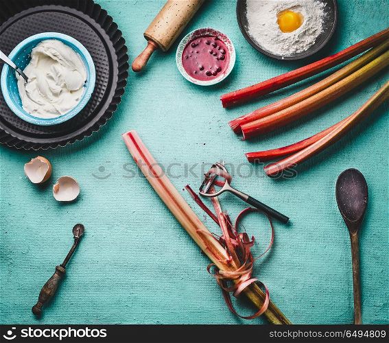 Rhubarb peeling. Fresh red rhubarb stalks with peeler on kitchen table background with cooking and baking tools, top view. Seasonal food concept