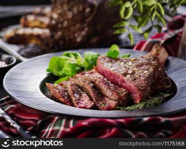 Rib eye. Tomahawk steak on the black plate with rosemary. Steak on the bone. Roasting - Rare. Entrecote.