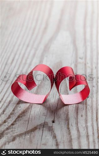 Ribbon hearts on wooden background. Two red small ribbon hearts on wooden background