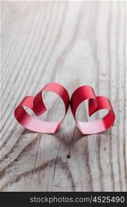 Ribbon hearts on wooden background. Two red small ribbon hearts on wooden background