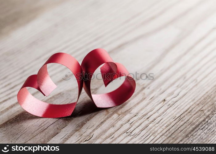 Ribbon hearts on wooden background. Two red small ribbon hearts on wooden background