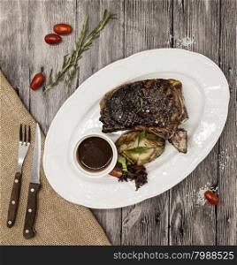 Ribeye steak from marble beef meat with vegetables and barbecue sauce. Served on a plate of black stone with fork and knife .. Ribeye steak from marble beef meat with vegetables and barbecue sauce. Served on a plate of black stone with fork and knife