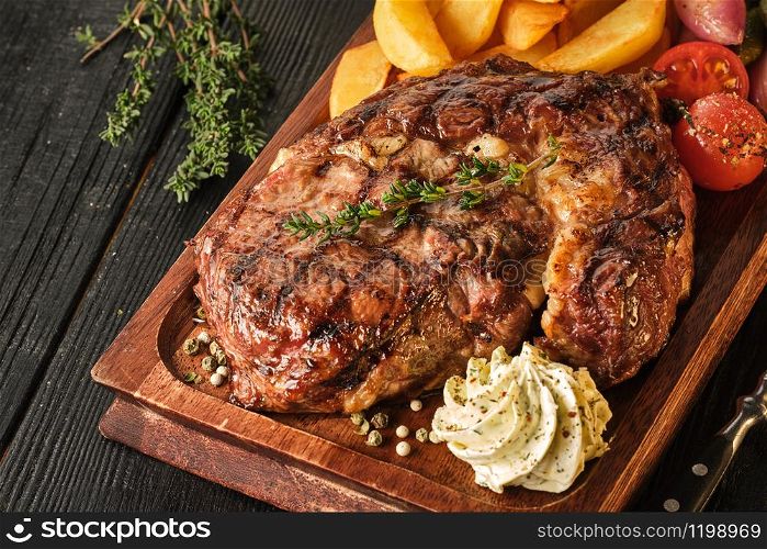 Ribeye steak with potatoes, onions and baked cherry tomatoes. Juicy steak with flavored butter.