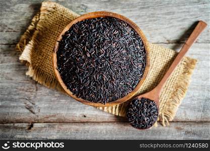 Rice berry in wooden bowl with spoon on wooden table, healthy food concept.
