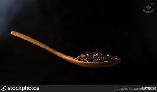 rice berry in wooden spoon on black background