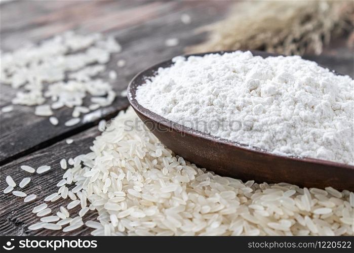 Rice flour in a bowl on a pile of white rice on old boards. Jasmine rice for cooking.. Rice flour in a bowl on a pile of white rice on old boards.