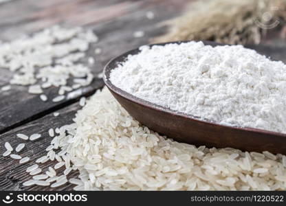 Rice flour in a bowl on a pile of white rice on old boards. Jasmine rice for cooking.. Rice flour in a bowl on a pile of white rice on old boards.