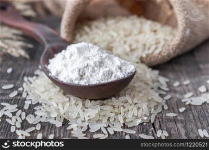 Rice flour in a spoon on a pile of white rice on old boards. Jasmine rice for cooking.. Rice flour in a spoon on a pile of white rice on old boards.