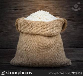rice in burlap sack on wooden background