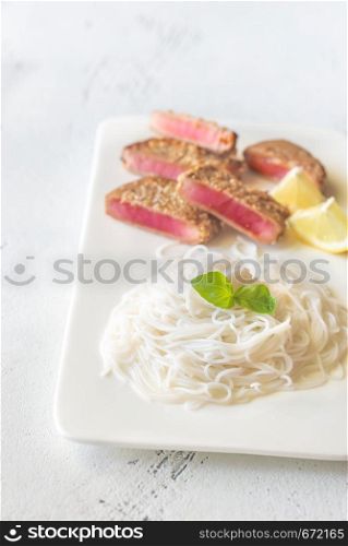 Rice noodles with fried tuna in sesame seeds on the white plate