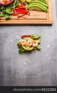 Rice paper rolls with vegetables and shrimp, cooking preparation on gray stone background, top view