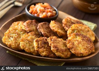 Rice patties or fritters made of cooked rice, carrot, onion, garlic and celery stalks, tomato sauce in the back, photographed with natural light (Selective Focus, Focus one third into the image)