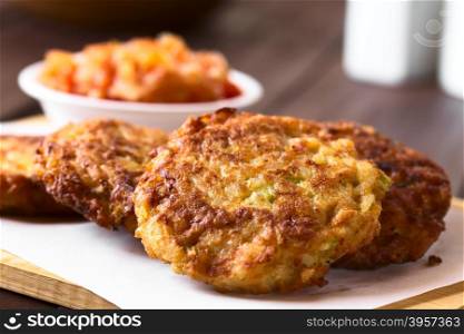 Rice patties or fritters made of cooked rice, carrot, onion, garlic and celery stalks, tomato sauce in the back, photographed with natural light (Selective Focus, Focus on the middle of the first patty)