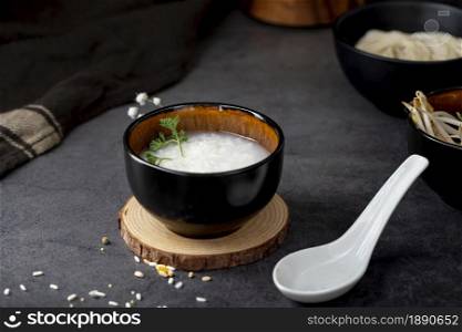 rice soup black bowl wooden support white spoon . Resolution and high quality beautiful photo. rice soup black bowl wooden support white spoon . High quality and resolution beautiful photo concept