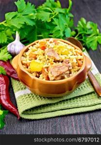 Rice with chicken, tomatoes, carrots, zucchini and garlic in a bowl on a wooden boards background