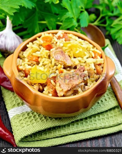 Rice with chicken, tomatoes, carrots, zucchini and garlic in a bowl on a dark wooden board