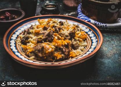 Rice with meat and vegetables in rustic plate on dark wooden table. Pilaf, national dish