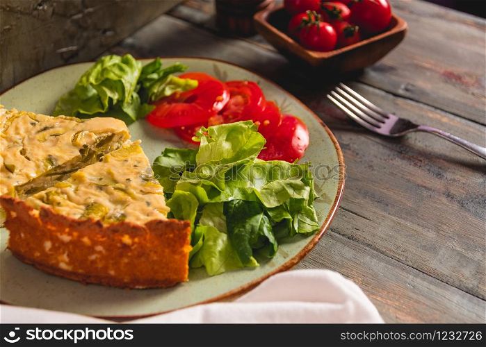 rich homemade cake with delicious zucchini and accompanied by salad of fresh tomatoes and leaves
