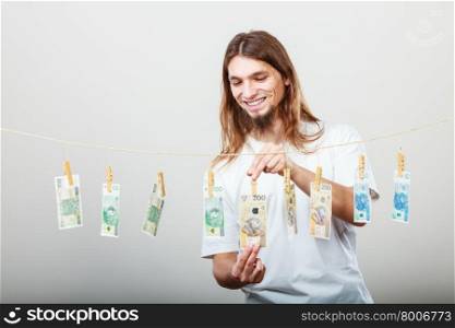 Rich man with laundry of money. Riches and fortune. Young happy man with a lot of money on grey background. Winning the lottery concept.