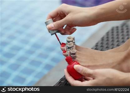 Rich woman pedicure. Woman painting nails using dollar bills sitting outdoors by the pool