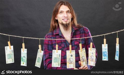 Riches and fortune. Young happy man with a lot of money on black background. Winning the lottery concept.. Rich man with laundry of money