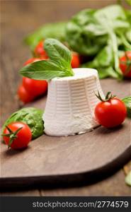 ricotta cheese with basil leaves and cherry tomatoes on wooden table