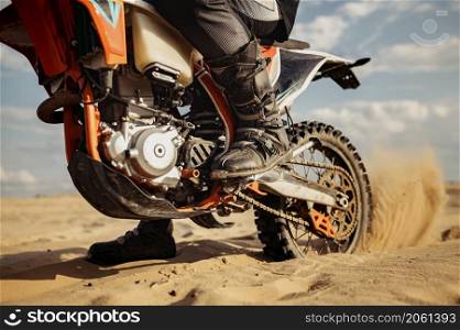 Rider driving in motocross race. Focus on skid rear wheel. Biker in ground track with dusty trail. Rider driving in motocross race skid wheel