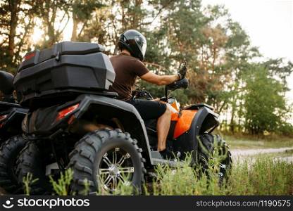 Rider in helmet and equipment on quad bike, front view, closeup. Male quadbike driver, atv riding. Rider in helmet on quad bike, front view, closeup