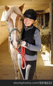 Rider with horse in stable. Young female rider with horse inside stable