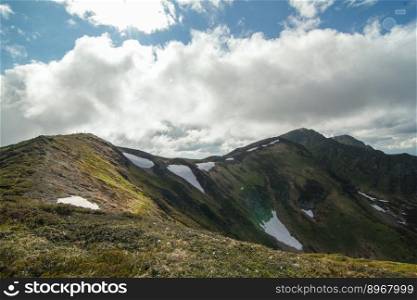Ridge with remaining glaciers landscape photo. Beautiful nature scenery photography with clouds on background. Ambient light. High quality picture for wallpaper, travel blog, magazine, article. Ridge with remaining glaciers landscape photo