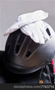 riding helmet and gloves  puted at saddle . equestrian riding concept. close up